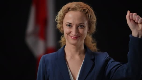 Vooraanzicht portret van zelfverzekerde glimlachende geïnspireerde vrouw met ondersteuning kracht gebaar te kijken naar de camera. Canadese activist of politicus poserend op zwarte achtergrond met nationale vlag. — Stockvideo