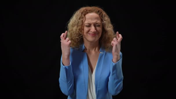 Kvinna korsande fingrar i hopp gest stänga ögon be på svart bakgrund. Porträtt av kaukasiska dam väntar på resultat prata be Gud om hjälp. — Stockvideo