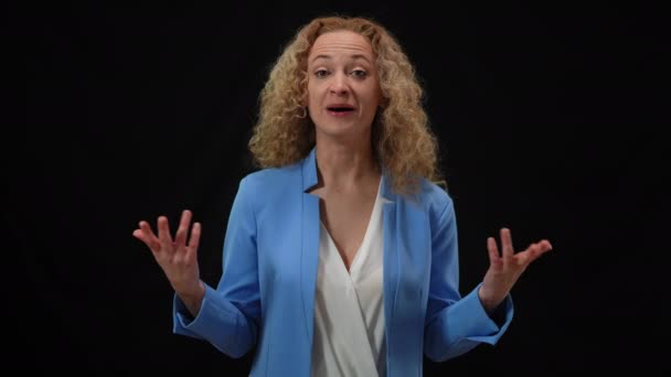 Mujer sonriente persuasiva en traje elegante que habla con gesto en el fondo negro. Retrato de confiado portavoz caucásico presentando idea. Confianza y concepto convincente. — Vídeo de stock