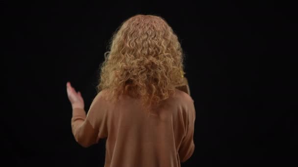 Back view of Caucasian woman talking on microphone gesturing. Medium shot of inspired motivated spokesperson presenting at black background. — Stock Video