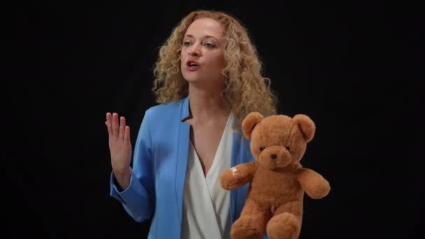 Confident woman holding teddy bear talking looking around persuading in kidnapping problem importance. Portrait of serious Caucasian female public speaker explaining danger of domestic violence. — Stock Video