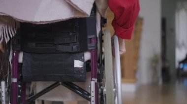 Üst düzey engelli bir adamın tekerlekli sandalyeyle kapalı merdivenlere gidişinin arka görüntüsü. Engelli, gri saçlı, beyaz, erkek emekli, oturma odasında. Rahatsızlık ve sakatlık kavramı.