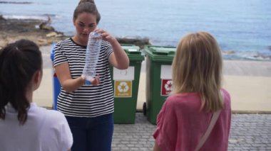 Kendine güvenen güzel beyaz kadın gönüllülere doğru plastik çöpleri topladığını gösteriyor. Konuşuyor ve hareket ediyor. Turizm merkezinde Akdeniz kıyılarını temizleyen ekip. Yavaş çekim.