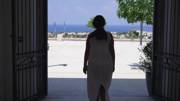 Vista posterior de la joven caucásica feliz en vestido blanco caminando a la plaza en el país mediterráneo levantando las manos en cámara lenta. Cámara en vivo sigue alegre relajado turista admirando la belleza de la naturaleza. — Vídeo de stock