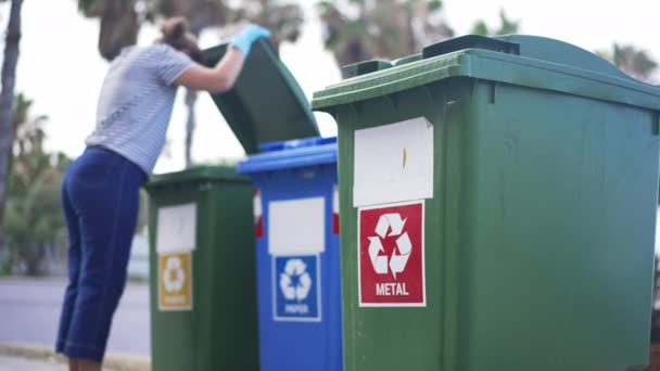 Vrijwilliger controleren van afval in afvalbakken voor gescheiden afvalinzameling op mediterrane resort. Jonge blanke vrouw op zoek naar containers buiten in slow motion. — Stockvideo