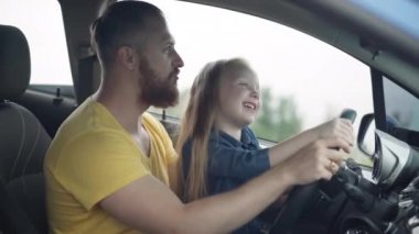 Mutlu baba, gülen küçük kızın başını öperken direksiyona geçmiş taklidi yapıyor. Beyaz sakallı adamı seven, arabasında neşeli bir kızla eğlenen..