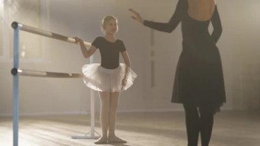 Gülümseyen motivasyonlu güzel kız hocaya bakarak hareketlerini açıklıyor. Kafkas öğrenci ve profesyonel öğretmenin sisli bale stüdyosunda portresi. Koreografi.