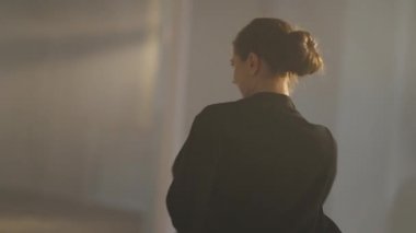 Kendinden emin bir bayan dansçı kameraya bakıyor ve kapalı alanda tutkulu bir şekilde dans ediyor. Ağır çekimde hareket eden mutlu beyaz kadın portresi. Canlı kamera.