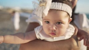 Akdeniz kıyısında tanınmayan annesiyle birlikte güneş ışığında uzanan sevimli, güzel bir kızın yakın çekimi. Gün batımında güzel bir çocuğun plajda ailesiyle portresi..