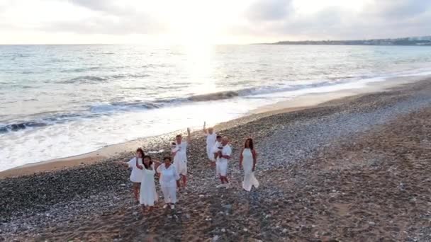 Zoom out of group of multigenerational Asian family waving smiling standing at sunset on picturesque Mediterranean sea shore. Gorgeous landscape at subtropical tourist resort with happy people resting — Stock Video