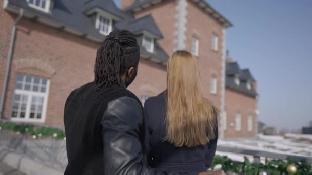 부유 한 아프리카 계 미국인 성공 한 남자 백인 여성에게 선물 집을 보여 주고 있어. 사랑많고 부유 한 남편 이 집 밖에서 아내를 위해 부동산을 제공 한다. 놀라움 과 럭셔리 개념. — 비디오