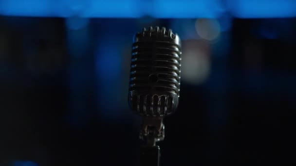 Gros plan microphone acoustique avec lumières de scène éteintes en arrière-plan. Équipement de concert professionnel noir dans l'obscurité après la fin de la performance à l'intérieur. Vie nocturne et divertissement. — Video