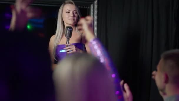 Artistică blondă subțire dansând și cântând cu microfonul pe scenă ca DJ roșcată de sex feminin în picioare la platou și o mulțime de oameni aplaudă. Steaua populară care cântă pe scenă . — Videoclip de stoc