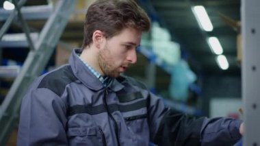 Esmer adam karton kutuda barkodu tarayıcı ile şehir sanayi deposunda tarıyor. Depoda ya da terminalde stokları kontrol eden konsantre yakışıklı Kafkas çalışanın portresi.