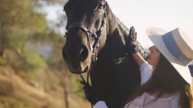 Güzel bir at kameraya bakarken boynunu yavaşça okşayan bir kadın gibi. Ormandaki dağ tepesinde duran Rus Mutluluk dövmeli zarif bir hayvan ve profesyonel Kafkas binicisi..