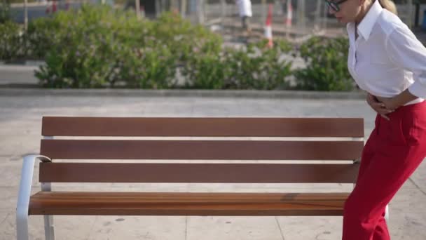 Bench in sunny city with unwell businesswoman having stomach pain sitting down asking help as people passing. Sad unhealthy Caucasian woman alone ignored by society. — Stock Video