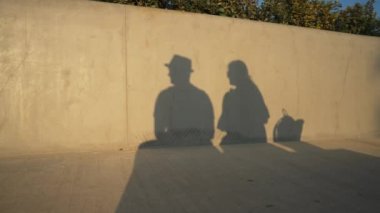 Gün ışığında öpüşen genç bir adamın ve kadının gölgeleri duvara yansıyor. Dışarıda güneşin altında birbirini seven romantik çiftin silueti. İlişki ve sonsuz aşk kavramı.