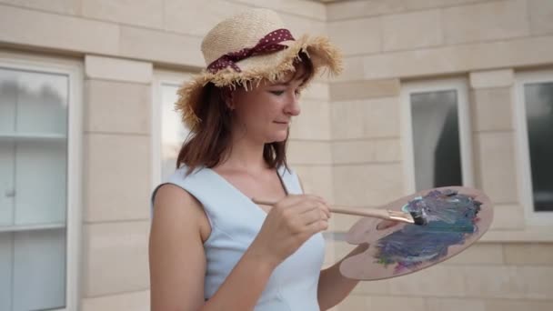 Jeune femme talentueuse imitant la peinture à la caméra au ralenti. Portrait d'une femme peintre caucasienne inspirée faisant des coups de pinceau à l'extérieur de la ville. Image point de vue. — Video