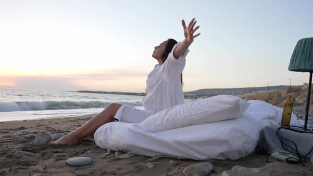 Joven joven confiada meditando en la pintoresca costa del mar Mediterráneo. Vista lateral amplia toma de encantadora dama delgada caucásica cerrando los ojos doblando las manos en cámara lenta sonriendo. Tranquilidad. — Vídeo de stock