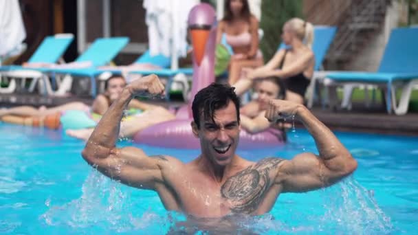 Widok z przodu portret przystojnego mężczyzny z Bliskiego Wschodu pokazujący gest siły patrząc na kamerę stojącą w błękitnym basenie. Szczęśliwy turysta pozowanie na świeżym powietrzu w zwolnionym tempie. Męskość. — Wideo stockowe