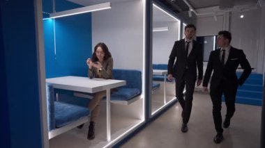 Kafkasyalı işadamları koridorda cam ofiste oturup akıllı telefondan internette sörf yapan bir iş kadınıyla dolaşıyorlar. İş yerindeki yoğun çalışanlar. Yavaş çekim.