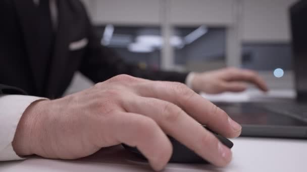 Närbild manliga kaukasiska hand med hjälp av datormus på kontoret i slow motion. Oigenkännlig man i formell kostym surfa Internet inomhus på arbetsplatsen. Modern teknik och trådlös sökning. — Stockvideo