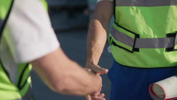 Erkek tasarımcı ve mimarın açık havada el sıkışması. Tanımlanamayan iki adam ağır çekimde el sıkışıyor güneşli bir günde depoda duruyorlar.. — Stok video