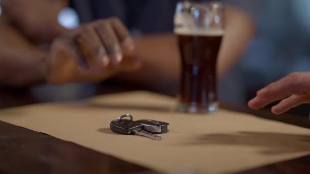 Zbliżenie klucza do samochodu przy barze z afroamerykańską męską ręką, gestykulującą zabronioną, nierozpoznawalną jazdę po pijanemu. Odpowiedzialny przyjaciel dbający o bezpieczeństwo. Kwestie społeczne. — Wideo stockowe