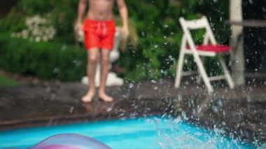 Canlı kamera, havuza atlayan neşeli çocukları yavaş çekimde mavi suya sıçrayan ve yüzerek uzaklaşan çocukları takip ediyor. Kaygısız beyaz kız ve erkek açık havada dalış yaparken eğleniyor..