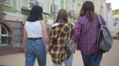 Arkaya bakan mutlu kız arkadaşlar şehir sokaklarında el ele yürüyüp konuşuyorlar. Kafkasyalı genç kız arkadaşlar üniversitede dersten sonra dışarıda sohbet ediyorlar. Yaşam tarzı ve eğlence..