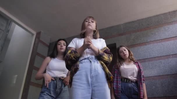 Нижній вигляд трьох агресивних кавказьких дівчат - підлітків, які говорять, погрожуючи комусь. Портрет школярок - підлітків, які знущаються. Підлітковість і агресія. — стокове відео