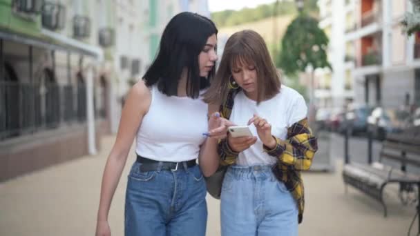 Nastolatki Kaukaskie dziewczyny rozmawiające spacery po mieście europejskim - szczegółowa mapa Portret pozytywnych uroczych nastolatków spacerujących razem na świeżym powietrzu. — Wideo stockowe