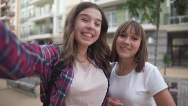 Két elbűvölő, vidám tinédzser blogger mosolyog a város utcáján. Szelfi kamera POV vidám szép magabiztos barátok blogolnak a szabadban. Életmód és barátság. — Stock videók