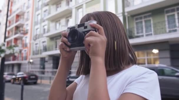 Freudiges talentiertes Teenager-Mädchen beim Fotografieren auf der Straße der Stadt, lachend. Porträt eines positiven selbstbewussten kaukasischen schönen Teenagers, der sein Hobby im Freien ausübt. Lebensstil und Hobbys der Generation Z. — Stockvideo