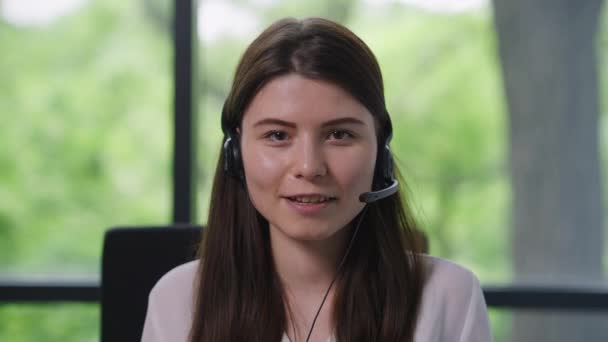 Sorrindo bela mulher caucasiana em fones de ouvido falando olhando para a câmera no chat de vídeo. Retrato de visão frontal de profissionais persuasivos que convencem colegas ou parceiros on-line em quarentena. — Vídeo de Stock