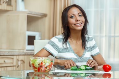 Güzel kadın modern mutfakta salatalık salatası için dilimleme 