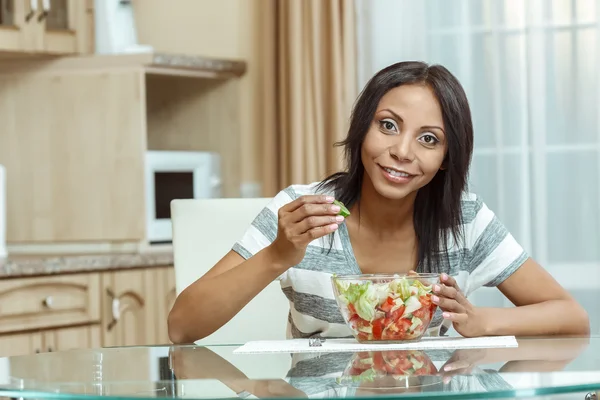Vacker kvinna äta färsk sallad i moderna kök — Stockfoto
