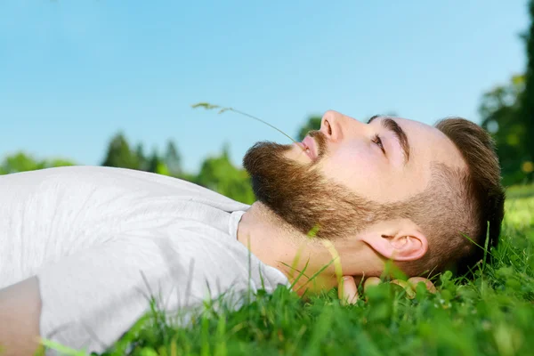 Jonge man liggen op het gras in park — Stockfoto