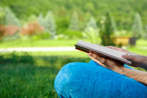 Genç adam parkta kitap okuyor.