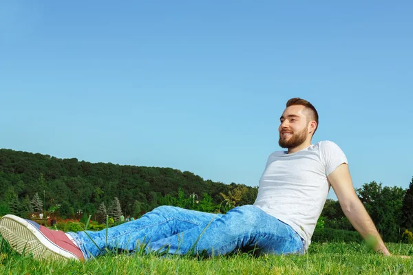 公園の草の上に横たわる若い男 — ストック写真