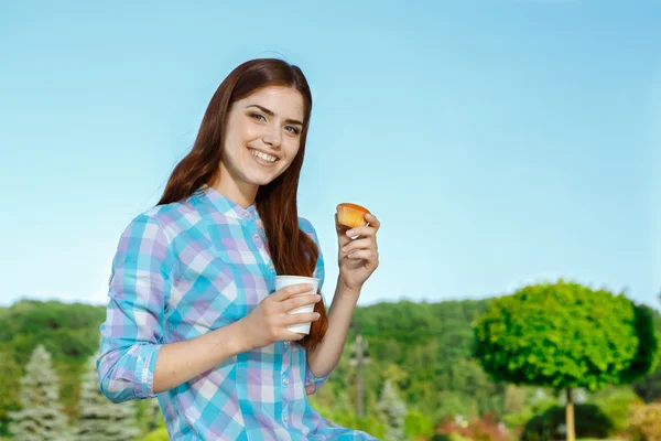 Vacker ung flicka med tårta och kaffe i parken — Stockfoto