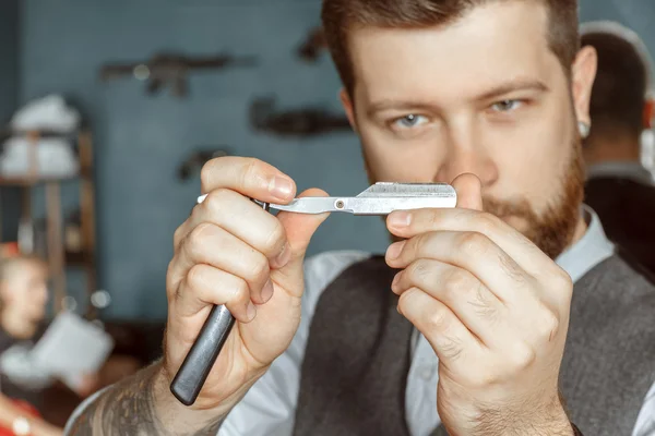 Barber testing the sharpness of a blade — Stock Photo, Image