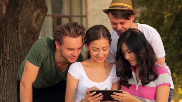 Menina mostrando seus amigos algum vídeo em um tablet — Vídeo de Stock