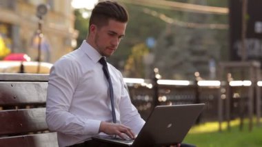 Genç adam parkta bir dizüstü bilgisayar ile çalışma