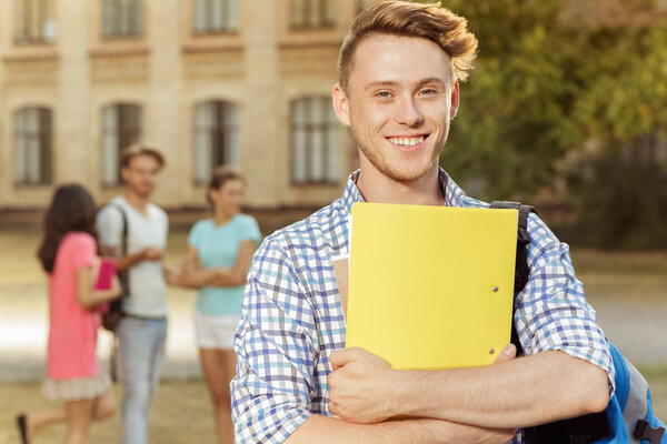 Young handsome guy holding a notebook and smiling eyes