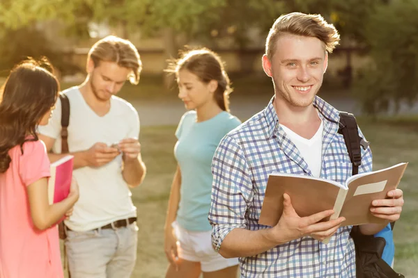 Young handsome guy holding a notebook and smiling eyes — Stock Photo, Image