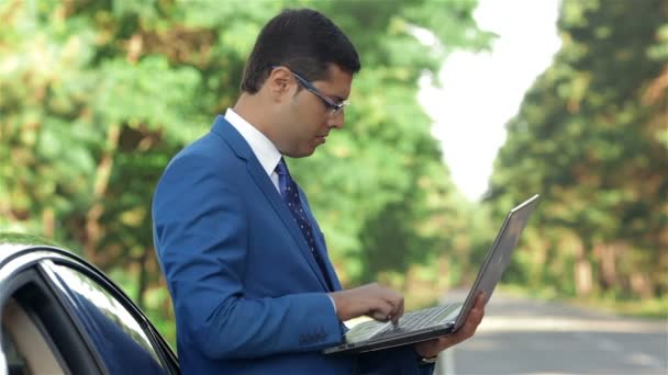 Empresario trabajando en el ordenador junto al coche — Vídeos de Stock