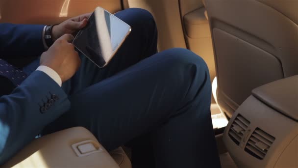 Бизнесмен сидит в машине и читает планшет — стоковое видео