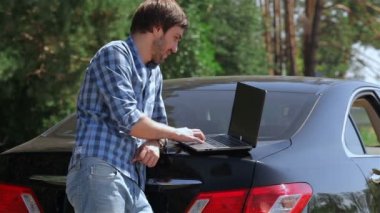 arabanın bagajına bilgisayarda çalışan adam
