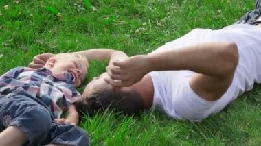 Baba ve oğul parkta çim üzerinde yalan